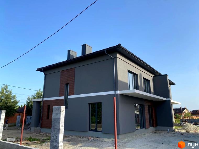 Зовнішній вигляд двоповерхового будинку сірого кольору з коричневими вставками на вулиці Волошкова. Навколо будинку видно будівельні роботи та елементи прибудинкової території.