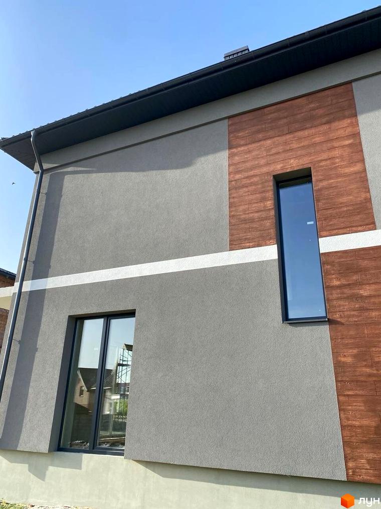 Фасад будинку з сірою штукатуркою та дерев'яними панелями, вікна на вулиці Волошкова. Зовнішній вигляд новобудови на вулиці Волошкова.