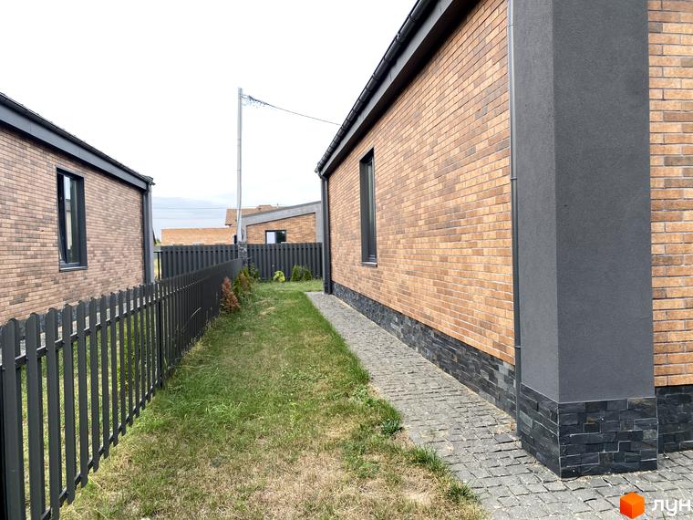 КМ Country Villa - котеджне містечко з цегляними будинками та доглянутою прибудинковою територією з газоном та парканом.