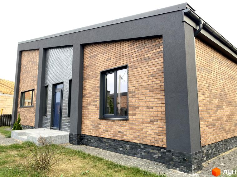 Котеджне містечко КМ Country Villa. Зовнішній вигляд будинку з цегляним фасадом, темними віконними рамами та сірими декоративними елементами. Прибудинкова територія з газоном та доріжками.