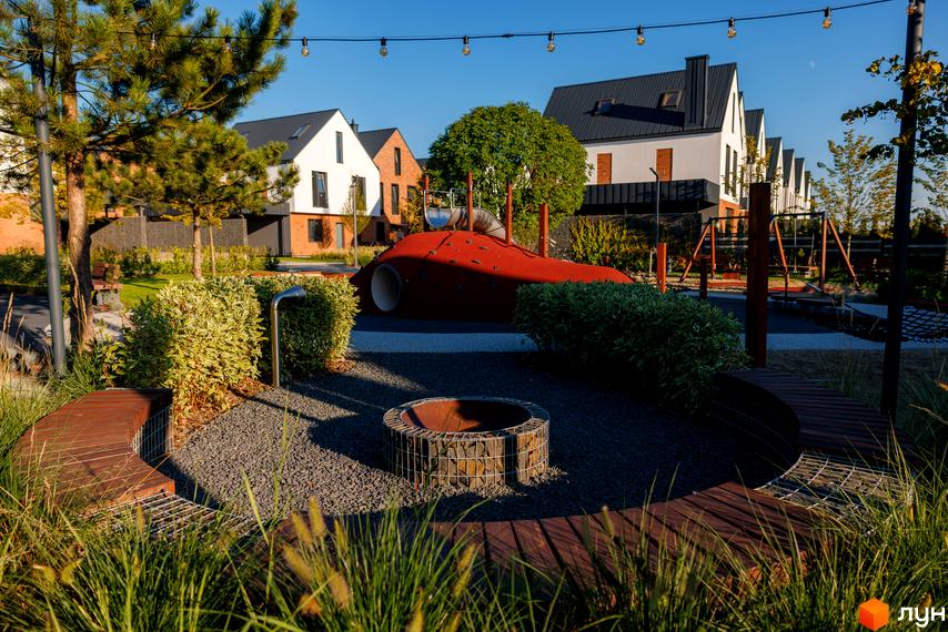 Котеджне містечко LAGOM: сучасні будинки з чорними дахами та зелена прибудинкова територія з дитячим майданчиком та зоною відпочинку.