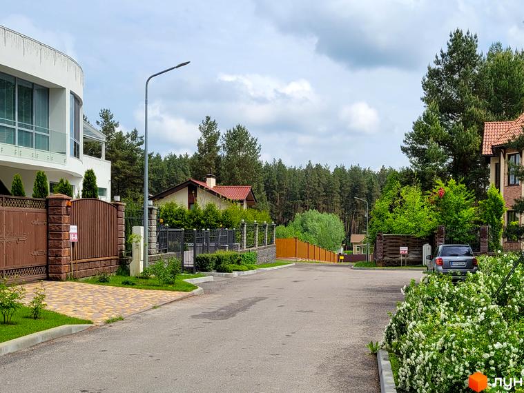 Зовнішній вигляд будинку в КМ Swisstown з прибудинковою територією, озелененням та доріжками.