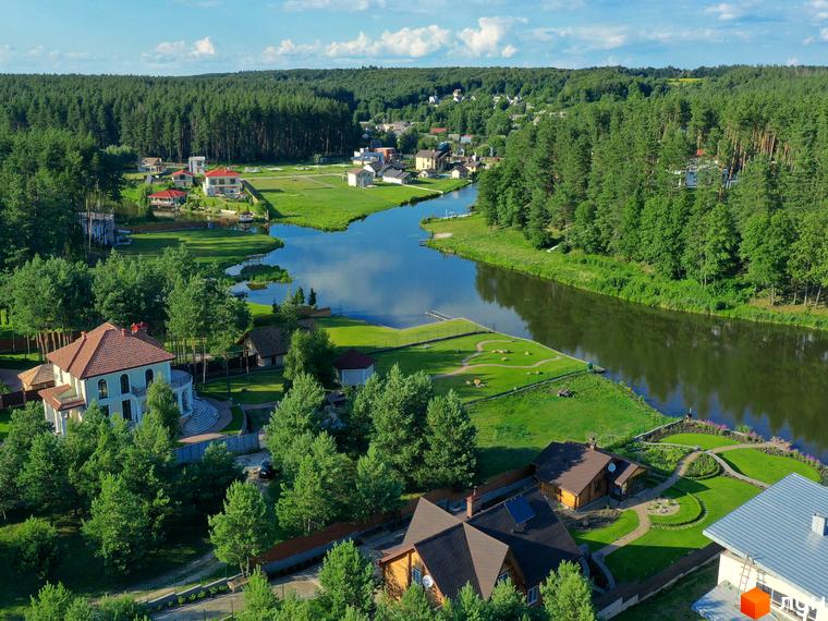 Котеджне містечко КМ Swisstown: розкішні будинки з червоними дахами біля озера та лісу. Прибудинкова територія з доглянутими газонами та доріжками.