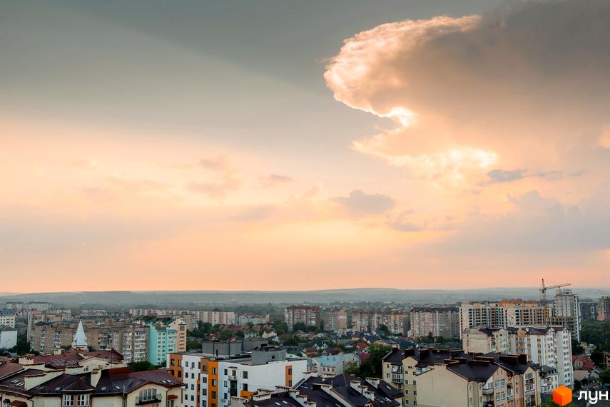 Вид на житловий комплекс SKYGARDEN з висоти пташиного польоту на тлі хмарного неба. Новобудова складається з багатоповерхових будинків з різнокольоровими фасадами.
