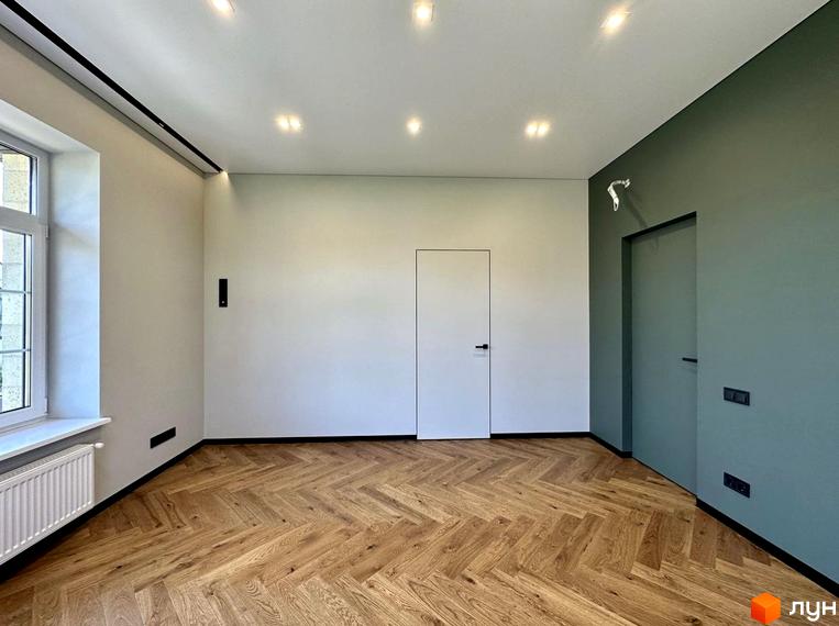 Простора вітальня з паркетною підлогою та двома дверима в житловому комплексі 