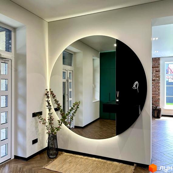 Просторий передпокій з круглим дзеркалом з підсвіткою та декоративною рослиною в плетеному кошику. Дизайн інтер'єру новобудови.