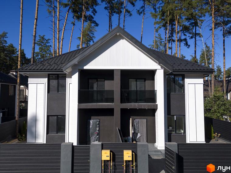 Сучасний двоповерховий дуплекс Toscana Home з чорним дахом та білими елементами фасаду, розташований серед високих сосен.