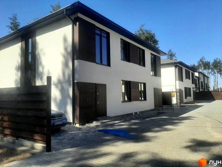 Котеджне містечко КМ Лісове-3: двоповерхові будинки з білою та темно-коричневою обробкою, великими вікнами. Прибудинкова територія з бруківкою та дерев'яним парканом.