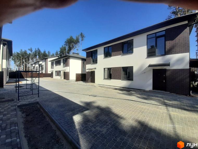 Котеджне містечко КМ Лісове-3: двоповерхові будинки з білою та темно-коричневою цегляною обробкою, великими вікнами. Прибудинкова територія з бруківкою та зеленими насадженнями.