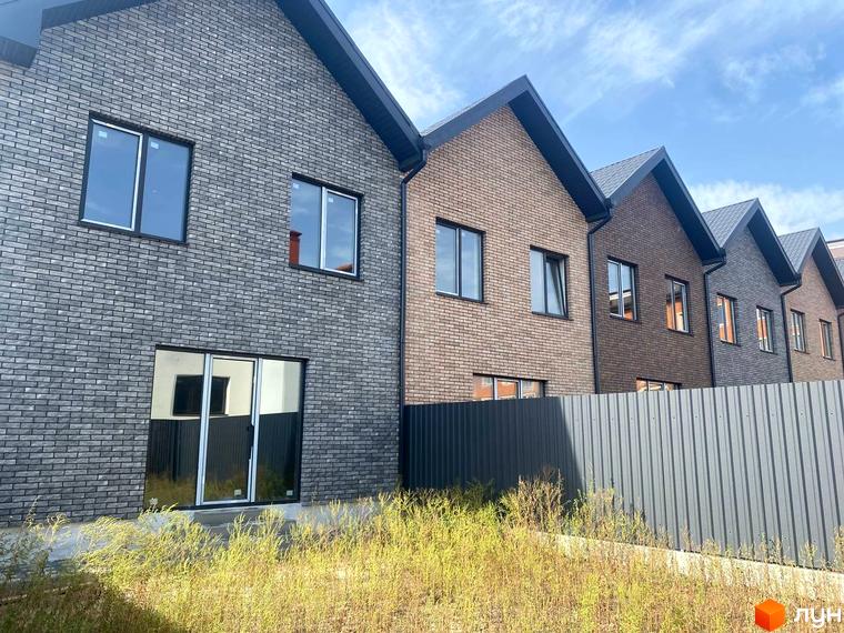 Зовнішній вигляд таунхаусів Чемпіон з цегляним фасадом та парканом. Навколо будівель зелена трава.