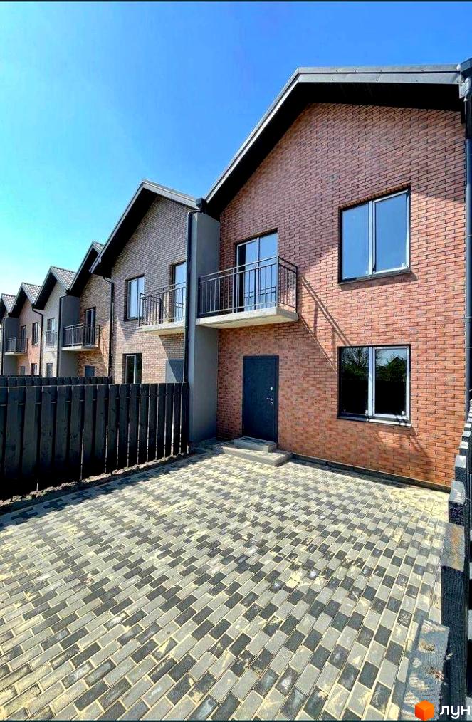 Зовнішній вигляд таунхаусів Чемпіон з цегляним фасадом та балконами. Прибудинкова територія з бруківки та дерев'яного паркану.