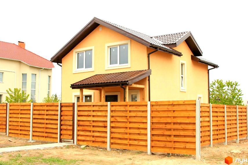 Двоповерховий будинок Котеджного містечка Софіївка світло-жовтого кольору з коричневим дахом. Перед будинком встановлено дерев'яний паркан.