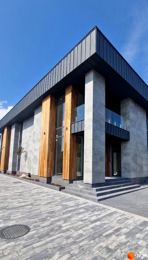 Зовнішній вигляд дуплексів Zubra House з сірою плиткою та дерев'яними елементами, вимощена сіра плитка перед будинком.