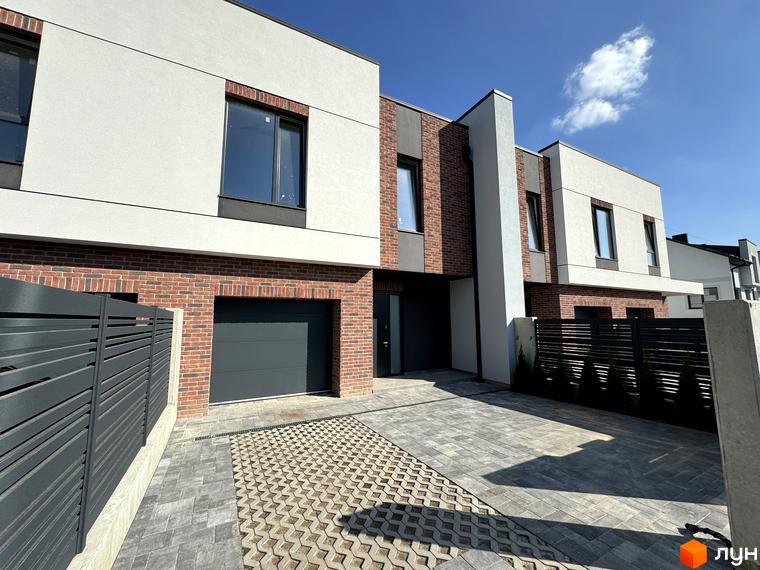 Зовнішній вигляд таунхаусів Loft House з цегляним фасадом та білими вставками, з прибудинковою територією, вимощеною плиткою.