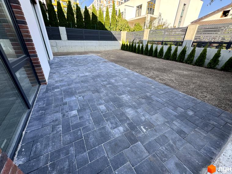 Зовнішній вигляд таунхаусів Loft House з бруківки та зеленої зони. Територія перед будинками вкрита плиткою та газоном, оточена туями та парканом.