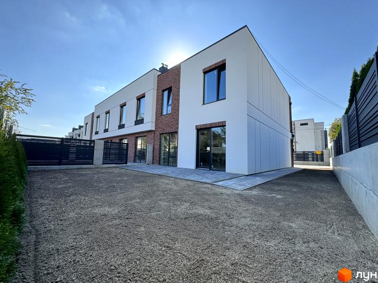 Таунхауси Loft House з білою та цегляною обробкою фасаду та прибудинковою територією з гравію та зеленими насадженнями.