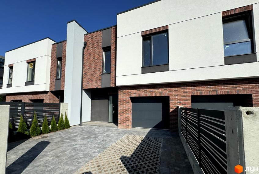 Таунхауси Loft House з цегляним фасадом та великими вікнами. Перед будинками розташований двір з бруківкою та парканом.