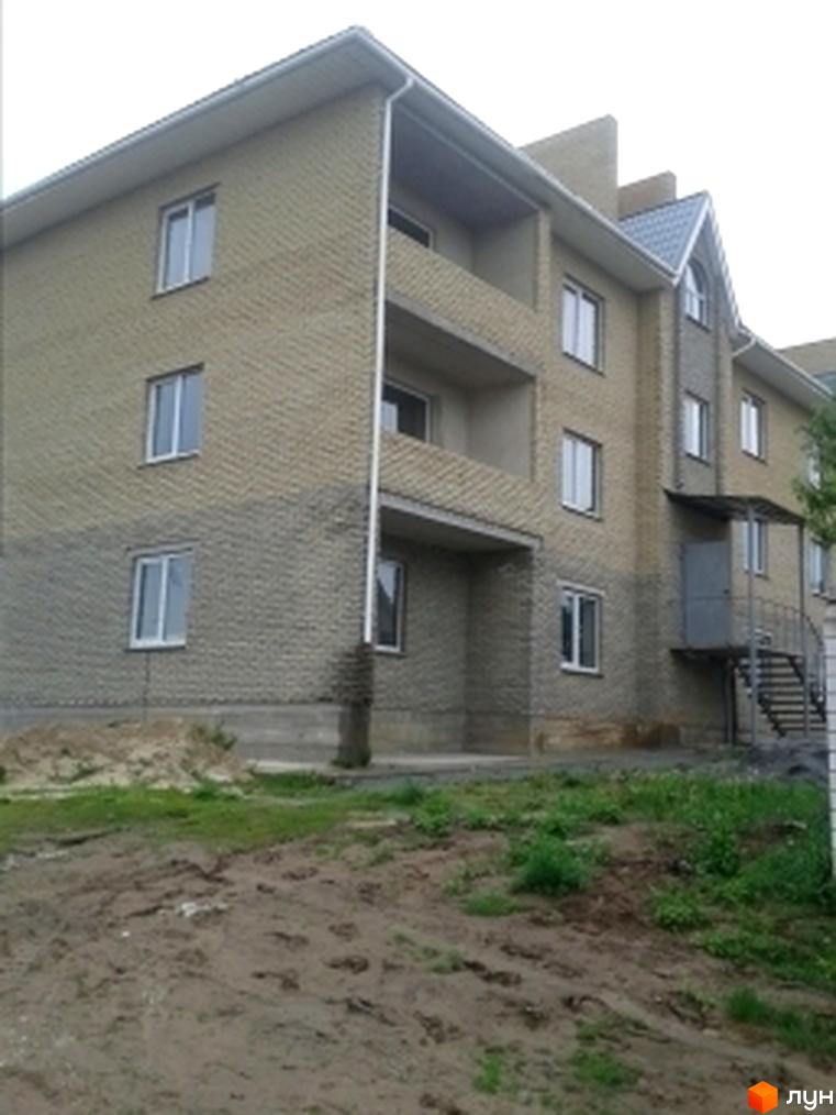 Житловий комплекс Сімплекс Сіті: багатоквартирний будинок з цегляними стінами, білими вікнами та балконами. Прибудинкова територія з ґрунтом та травою.
