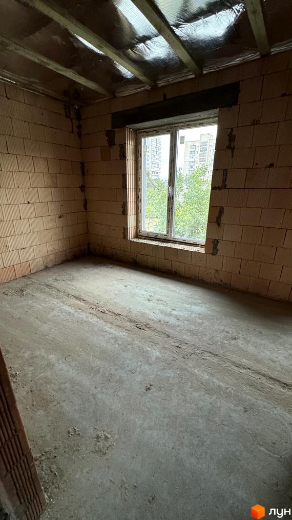 Будівельний проєкт Таунхауси А56: цегляні стіни, бетонна підлога та вікно з видом на дерева та багатоповерхівки.