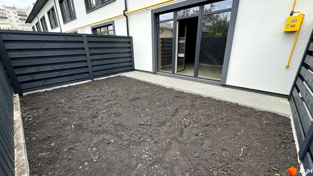 Зовнішній вигляд таунхаусів А56 з чорним парканом та доглянутою прибудинковою територією. Сучасна новобудова з великими вікнами та газовим підключенням.