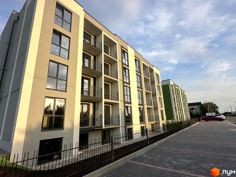 Зовнішній вигляд новобудови ЖК Brickwood 2 з балконами та великими вікнами, парковка перед будинком.