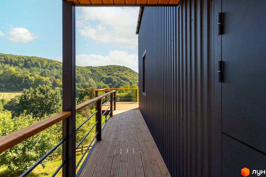 Котеджне містечко Схили: сучасний будинок з металевим фасадом та дерев'яною терасою на тлі зелених пагорбів. Насолоджуйтесь краєвидами з власної тераси.