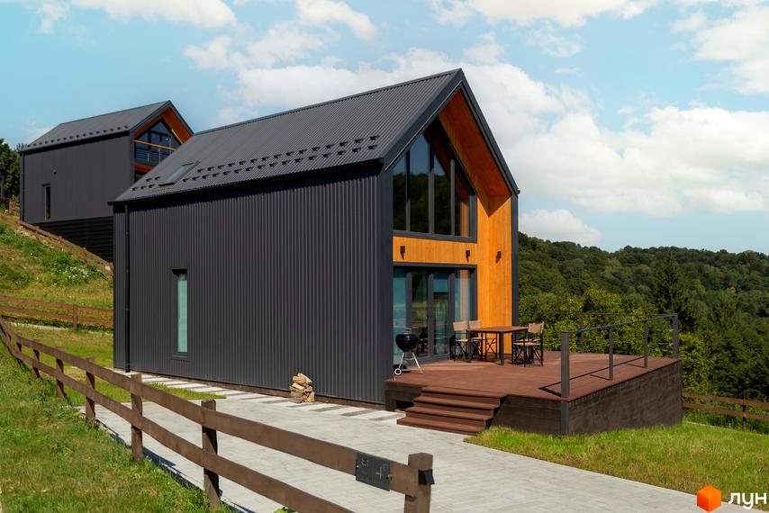Котеджне містечко Схили: сучасна архітектура з великими вікнами та дерев'яними елементами, простора тераса з меблями та мангалом, оточена зеленню.