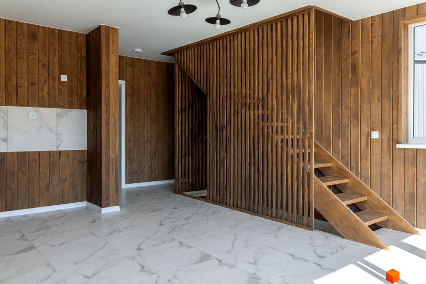 Інтер'єр будинку в котеджному містечку КМ Схили з дерев'яними стінами та сходами. Підлогове покриття - мармурова плитка.