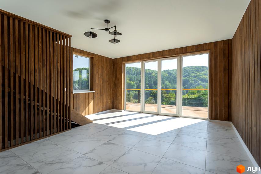 Просторий зал з панорамними вікнами та дерев'яними елементами в Котеджному містечку Схили, що виходить на зелені схили гір. Підлога з мармурової плитки відбиває сонячне світло, створюючи світлу атмосферу.