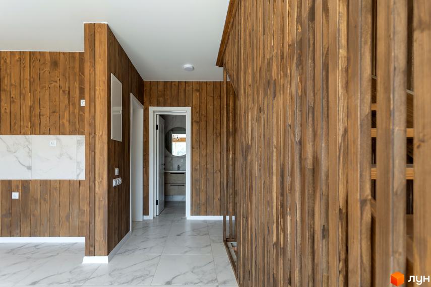 Інтер'єр котеджного містечка Схили з дерев'яними стінами та мармуровою плиткою на підлозі. Відкритий дверний отвір веде до ванної кімнати з круглим дзеркалом.