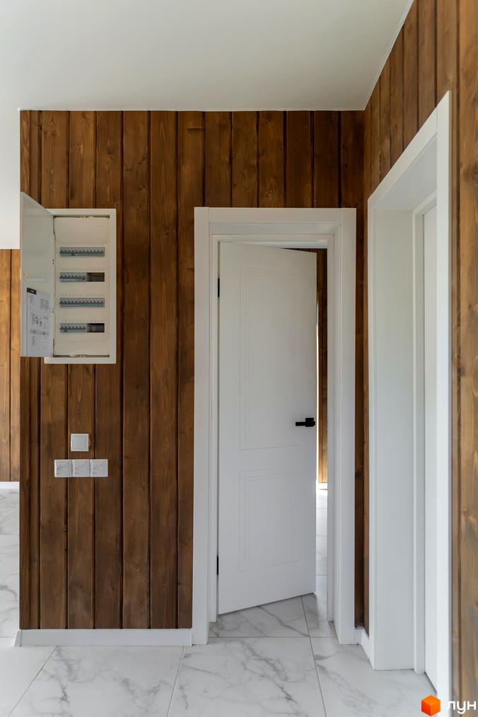 Інтер'єр квартири в житловому комплексі КМ Схили з дерев'яними панелями на стінах та білими дверима.
