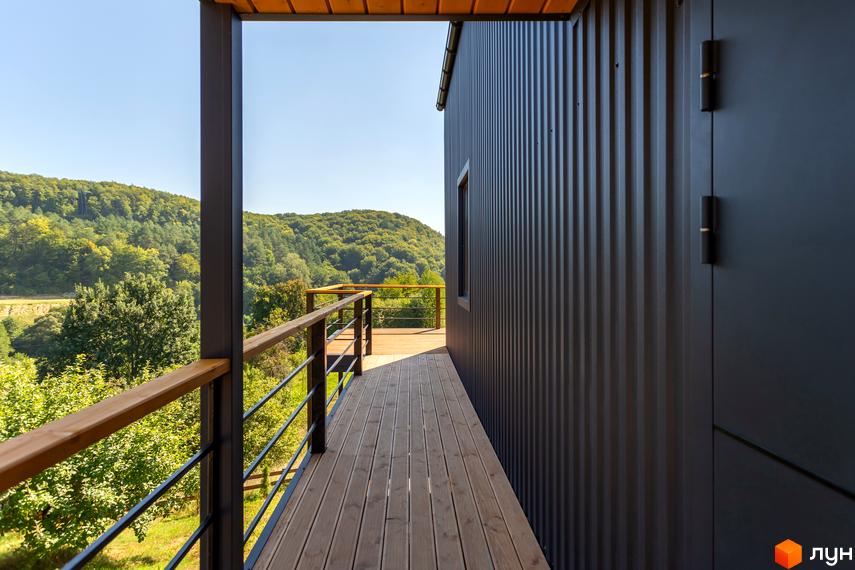 Котеджне містечко Схили: вид з тераси на зелені пагорби. Зовнішній вигляд будинку з металевим фасадом та дерев'яною терасою.