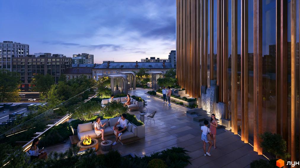 Тераса житлового комплексу THE ONE з зонами відпочинку та зеленими насадженнями на фоні міської забудови вечірнім часом. Сучасна архітектура будівлі з дерев'яними елементами.
