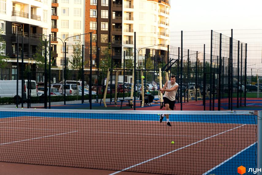 Житловий комплекс Синергія Сіті з сучасними фасадами та спортивним майданчиком для гри в падел-теніс.