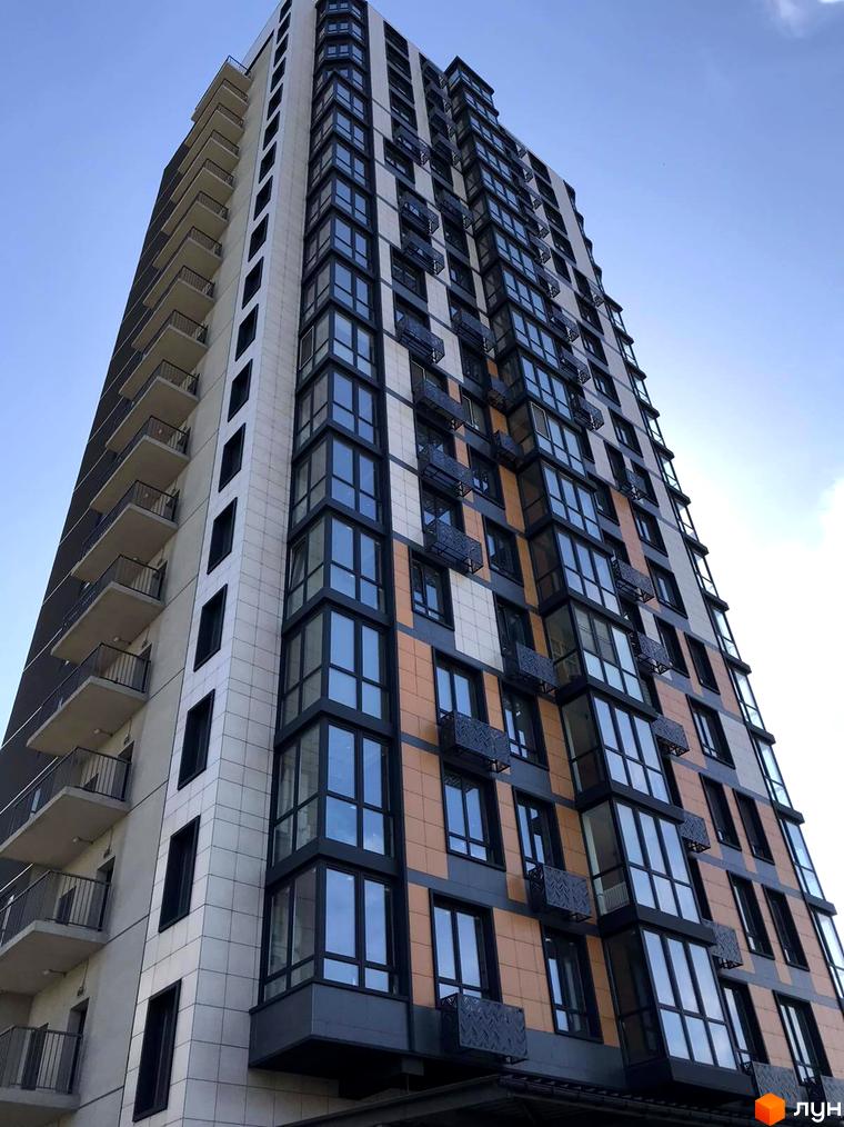 Зовнішній вигляд новобудови ЖК River Hall з балконами та панорамними вікнами на фоні блакитного неба. Будівельний проєкт з сучасною архітектурою.