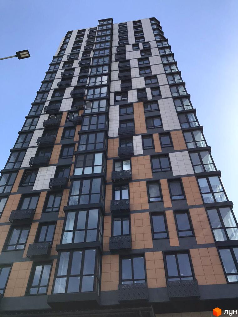 Зовнішній вигляд новобудови ЖК River Hall з фасадом, що комбінує сірі, білі та теракотові панелі, та великими панорамними вікнами.