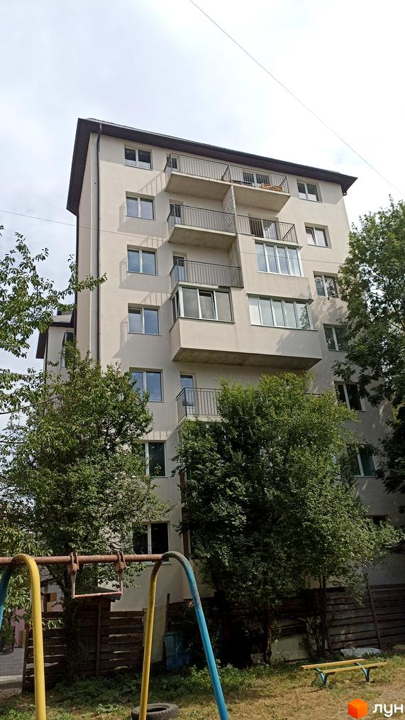 Зовнішній вигляд будинку на вулиці Лозовецька з балконами та вікнами, на прибудинковій території видно дитячий майданчик та зелені насадження.