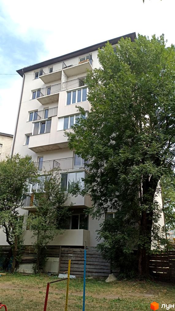 Зовнішній вигляд будинку на вулиці Лозовецькій з балконами та вікнами, оточений деревами та зеленою зоною.