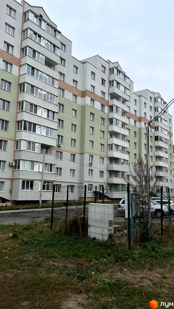 Багатоповерховий будинок на вул. Сергія Зулінського з сіро-зеленим фасадом та балконами. Перед будинком видно зелений паркан та траву.
