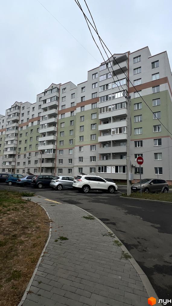 Житловий комплекс на вул. Сергія Зулінського: багатоповерховий будинок з сірим, зеленим та коричневим фасадом. Прибудинкова територія з парковкою та тротуаром.