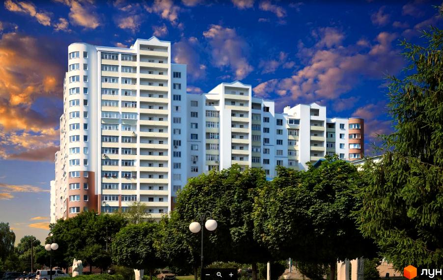 Новобудова Княжа гора: багатоповерховий житловий комплекс білого кольору з балконами та округлою коричневою секцією, оточений зеленими деревами.