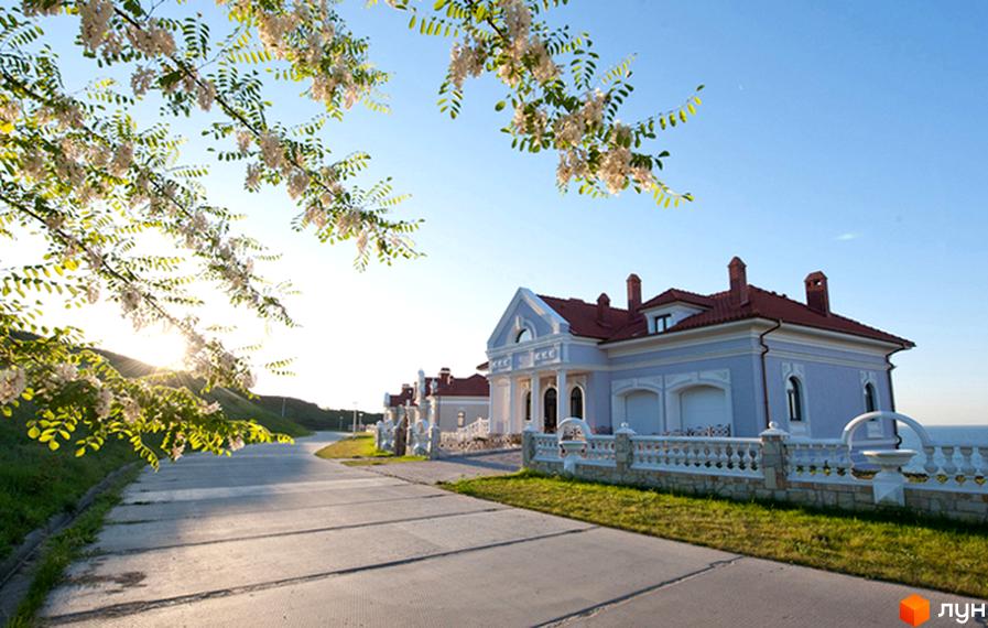 Зовнішній вигляд будинку житлового комплексу КМ Сосновий берег з прибудинковою територією та зеленими насадженнями.