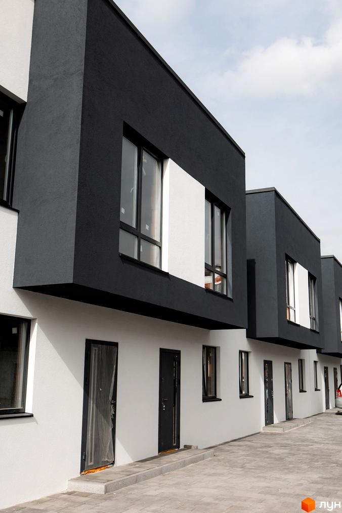 Фасад таунхаусів SDG Bilohorodka з чорно-білим оздобленням. Перед будинком викладена тротуарна плитка.