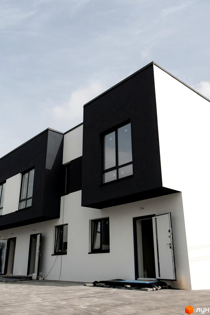 Зовнішній вигляд таунхаусів SDG Bilohorodka з чорно-білим фасадом. Перед будинками облаштована територія.