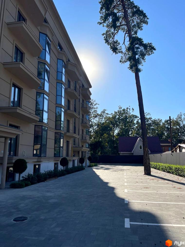 Житловий комплекс Monaco: фасади будівель з балконами та панорамними вікнами, парковка з деревом посередині.