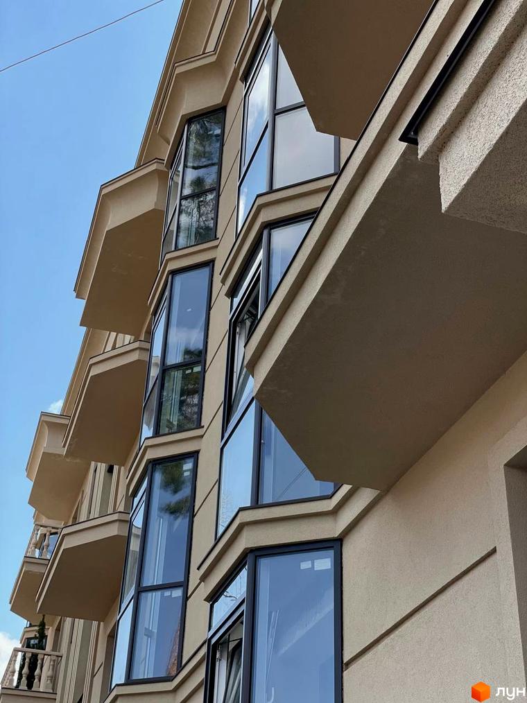 Фасад житлового комплексу Monaco з еркерними вікнами та балконами. Зовнішній вигляд новобудови з бежевим оздобленням.