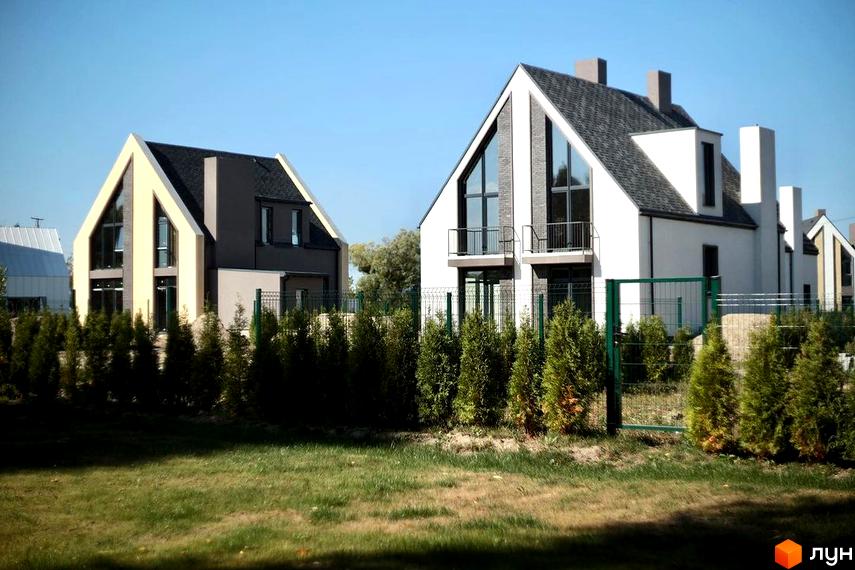 Котеджне містечко BELLAGGO: двоповерхові будинки з темним дахом та великими вікнами, огороджені парканом та оточені туями.