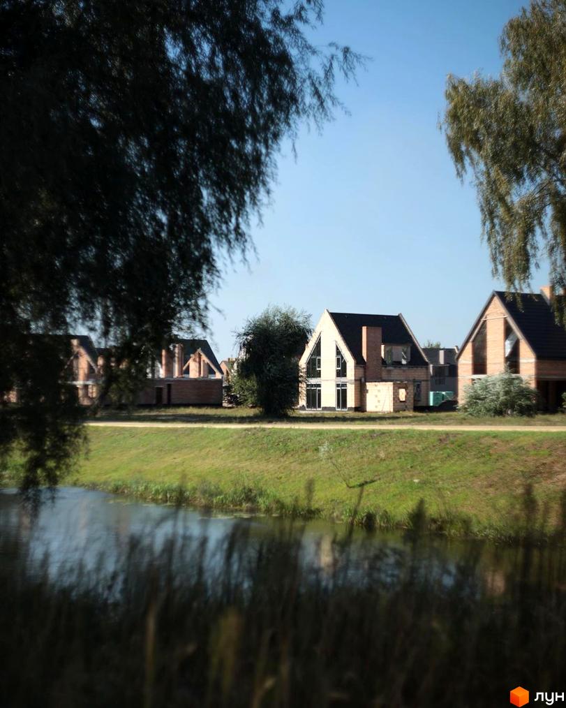 Котеджне містечко BELLAGGO з цегляними фасадами та темними дахами, розташоване біля водойми та зеленої зони.