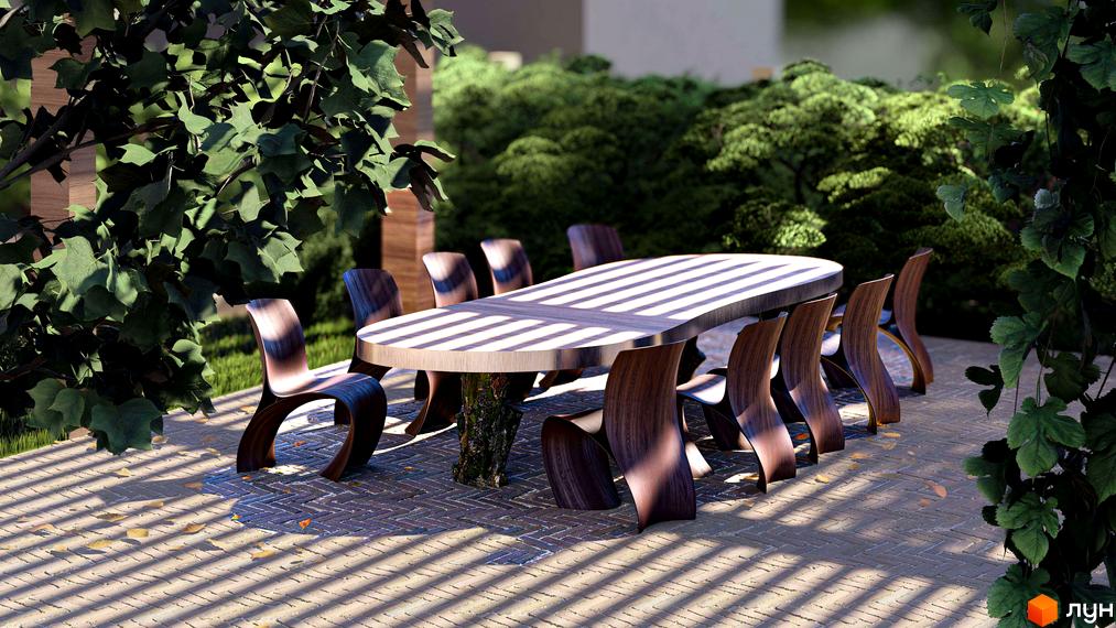 Зона відпочинку з овальним столом та дерев'яними стільцями на брукованій території Житлового комплексу Минай, освітлена смугами сонячного світла серед зелені.