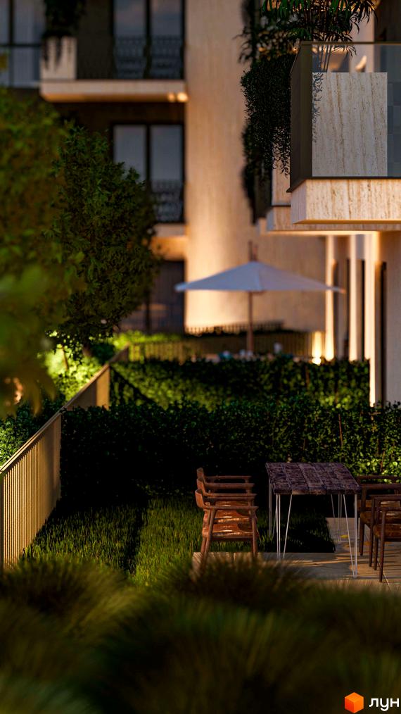 Вечірній фасад Житлового комплексу Минай з балконами. Прибудинкова територія: зелений газон, огорожа, освітлена зона відпочинку з меблями.